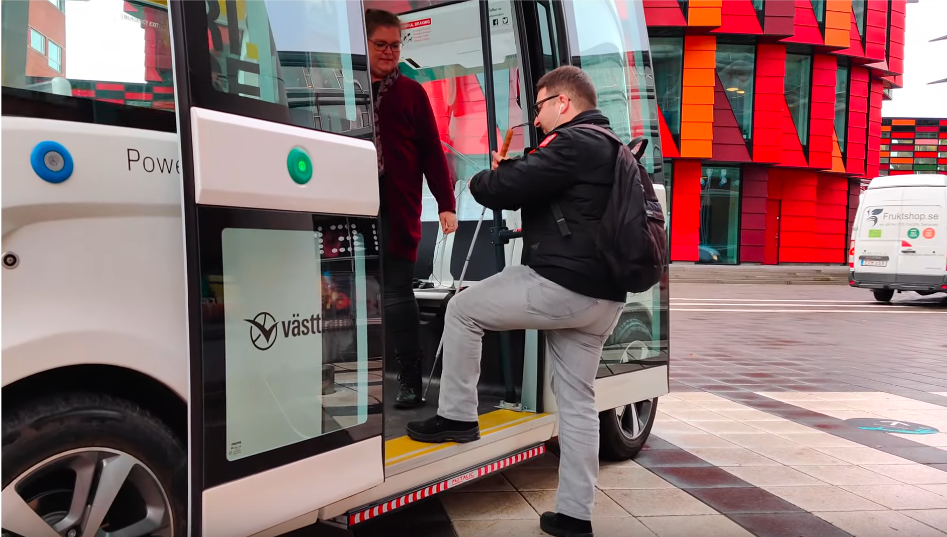 A man with a blind cap stepping on to an autonomous bus. 